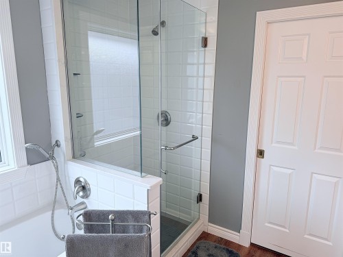 Glass-enclosed shower with subway tile surround, complementing a separate soaking tub with a handheld shower fixture - 915 Picard Drive Nw, Edmonton, AB 