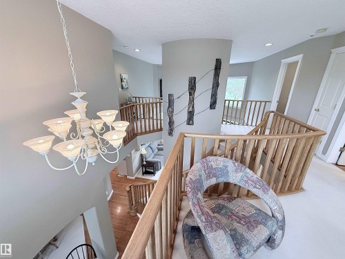Multi-level interior featuring a grand chandelier and light wood railings - 915 Picard Drive Nw, Edmonton, AB 