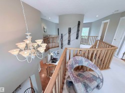 Multi-level interior featuring a grand chandelier and light wood railings - 