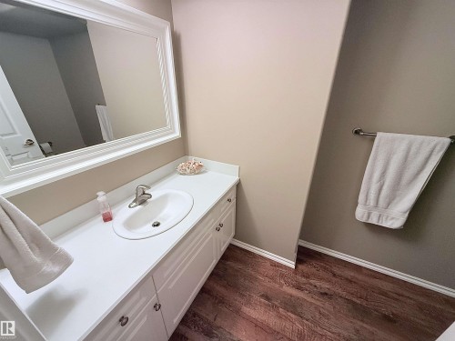 Vanity area featuring a white countertop with an undermount sink, brushed nickel faucet, and a large framed mirror - 915 Picard Drive Nw, Edmonton, AB 