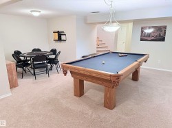 Spacious lower level featuring plush carpeting, recessed lighting, and a prominent central light fixture - 