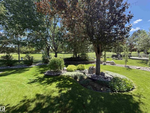 Expansive grounds featuring a manicured lawn, mature trees, and decorative rock landscaping - 915 Picard Drive Nw, Edmonton, AB 