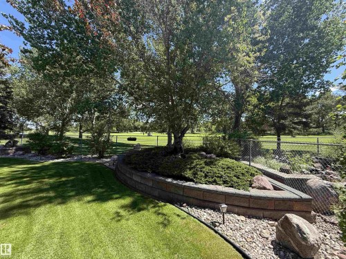 Manicured lawn with a curved paver retaining wall and integrated landscaping - 915 Picard Drive Nw, Edmonton, AB 