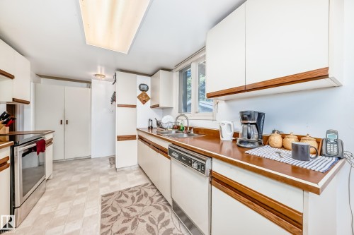 Kitchen featuring white cabinetry with wood-finish accents, wood-finish countertops, stainless steel electric range, and a built-in dishwasher - 6804 102A Avenue, Edmonton, AB 