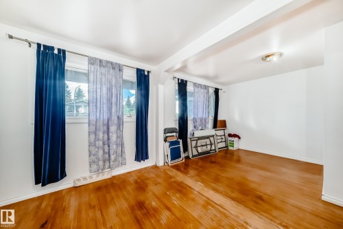 Bright interior space featuring polished wood-finish flooring, white walls, and multiple windows allowing ample natural light - 6804 102A Avenue, Edmonton, AB 