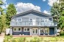 Modern facade featuring a second-story balcony with glass railing, stone accent pillars, double entry doors with oval glass inserts, multiple windows, and a partial front yard - 6804 102A Avenue, Edmonton, AB 