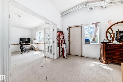 Vaulted white ceilings featuring exposed ductwork, a white paneled door, and a light-filled window - 6804 102A Avenue, Edmonton, AB 