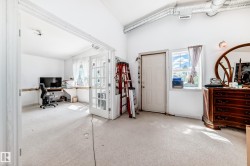 Vaulted white ceilings featuring exposed ductwork, a white paneled door, and a light-filled window - 