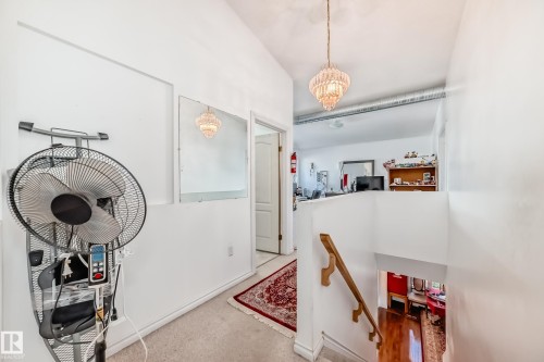 Upper-level hallway with carpet flooring and a crystal chandelier - 6804 102A Avenue, Edmonton, AB 