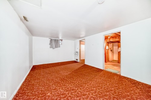 Spacious interior with white walls, patterned carpet, and two doorways leading to additional rooms - 6804 102A Avenue, Edmonton, AB 
