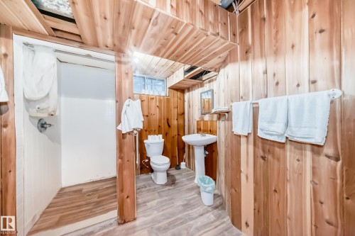 Bathroom featuring wood-paneled walls and ceiling, a pedestal sink, and a shower stall - 6804 102A Avenue, Edmonton, AB 