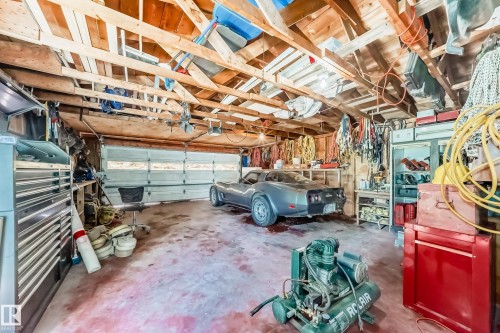 Garage space featuring an exposed wood beam ceiling, concrete flooring, and multiple storage options - 6804 102A Avenue, Edmonton, AB 