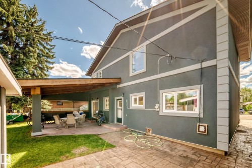 Rear exterior featuring a covered patio, stucco siding, and multiple windows - 6804 102A Avenue, Edmonton, AB 