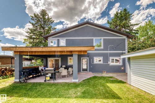 Rear exterior featuring a covered patio with a wooden overhead structure and paved flooring - 6804 102A Avenue, Edmonton, AB 