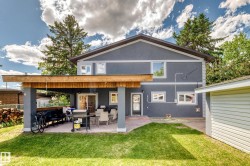 Rear exterior featuring a covered patio with a wooden overhead structure and paved flooring - 
