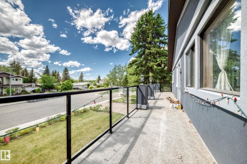 Exterior balcony featuring a glass and metal railing, concrete flooring, and exterior wall sconces - 6804 102A Avenue, Edmonton, AB 