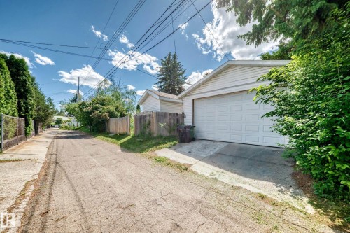 Detached two-car garage with white paneled door, horizontal siding, and a gabled roof - 6804 102A Avenue, Edmonton, AB 