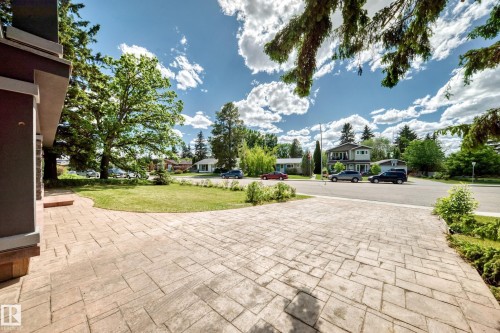Stamped concrete driveway and walkway with a manicured front lawn and mature trees - 6804 102A Avenue, Edmonton, AB 