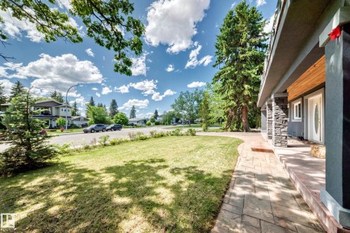 Front entry featuring a stamped concrete walkway, stone-clad columns, and a wood-paneled ceiling - 6804 102A Avenue, Edmonton, AB 