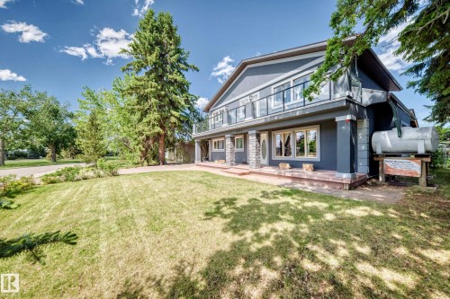 Two-story residence featuring a gray exterior with stone accents and a second-level balcony with a glass railing - 6804 102A Avenue, Edmonton, AB 