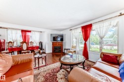 Hardwood-finish flooring extending into the dining area, large picture windows, wood-finish fireplace mantel with an electric insert, and white textured ceilings - 