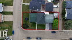 Corner lot property featuring a large grassy yard, mature tree, and a concrete driveway - 