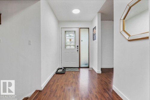 Entryway featuring wood-finish flooring, a white entry door with decorative glass, and a frosted glass sidelight - 712 Lee Ridge Road, Edmonton, AB 