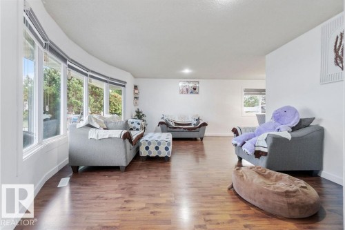 Spacious living area featuring wood-finish flooring, white walls, and a large bay window with multiple panes - 712 Lee Ridge Road, Edmonton, AB 