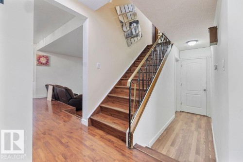 Staircase featuring wood-finish treads and an ornamental metal railing - 712 Lee Ridge Road, Edmonton, AB 