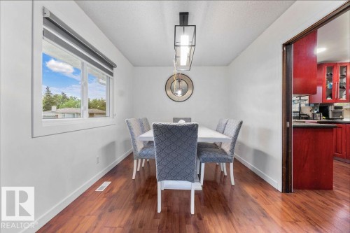 Hardwood-finish flooring enhancing the bright dining area with a modern linear chandelier and a large window - 712 Lee Ridge Road, Edmonton, AB 