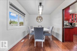 Hardwood-finish flooring enhancing the bright dining area with a modern linear chandelier and a large window - 