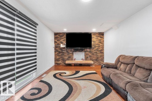 Living area featuring a brick accent wall, recessed lighting, and wood-finish flooring - 712 Lee Ridge Road, Edmonton, AB 