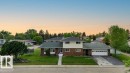 Split-level residence featuring a brick and siding exterior, front lawn, mature landscaping, paved driveway, and an attached two-car garage - 712 Lee Ridge Road, Edmonton, AB 