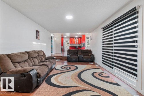 Bright living area featuring wood-finish flooring and a large window with horizontal striped blinds - 712 Lee Ridge Road, Edmonton, AB 
