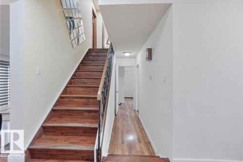Wood-finish staircase with black metal balusters and a light wood handrail - 712 Lee Ridge Road, Edmonton, AB 