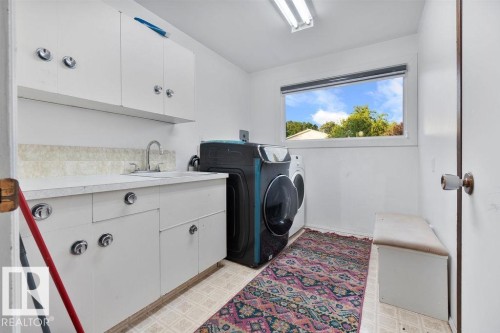 Utility room with white cabinetry, a built-in sink, and a large window - 712 Lee Ridge Road, Edmonton, AB 