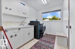 Utility room with white cabinetry, a built-in sink, and a large window - 