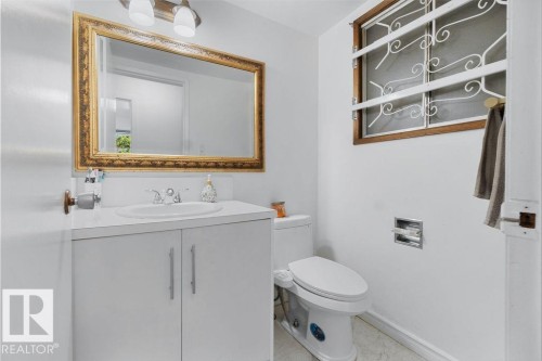White vanity with integrated sink, brass-framed mirror, and two-light fixture - 712 Lee Ridge Road, Edmonton, AB 