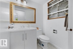 White vanity with integrated sink, brass-framed mirror, and two-light fixture - 