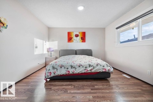 Spacious room featuring wood-finish flooring, white walls, and a large window - 712 Lee Ridge Road, Edmonton, AB 
