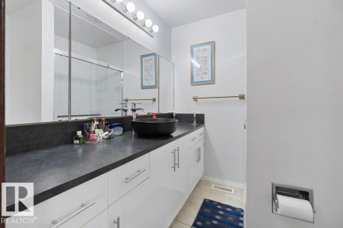 Bathroom vanity featuring a vessel sink, dark countertop, and white cabinetry with brushed nickel hardware - 712 Lee Ridge Road, Edmonton, AB 