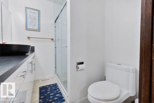 Bathroom featuring a contemporary vessel sink, dark countertop, and white cabinetry with brushed nickel hardware - 712 Lee Ridge Road, Edmonton, AB 