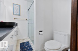 Bathroom featuring a contemporary vessel sink, dark countertop, and white cabinetry with brushed nickel hardware - 
