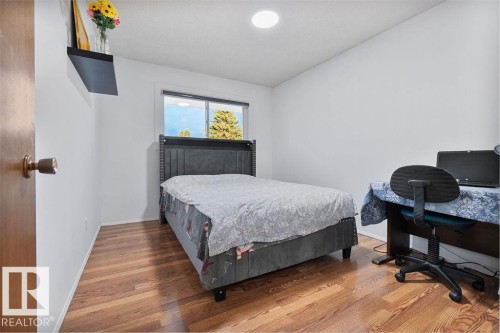 Bright interior room featuring wood-finish flooring, white painted walls, a window with exterior visibility, and a built-in ceiling light fixture - 712 Lee Ridge Road, Edmonton, AB 