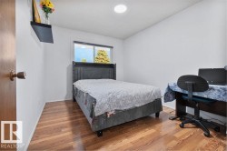 Bright interior room featuring wood-finish flooring, white painted walls, a window with exterior visibility, and a built-in ceiling light fixture - 