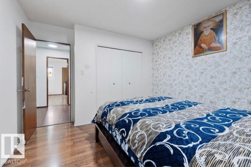 Bedroom featuring wood-finish flooring, patterned accent wall, and built-in bi-fold closet doors - 712 Lee Ridge Road, Edmonton, AB 