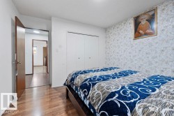 Bedroom featuring wood-finish flooring, patterned accent wall, and built-in bi-fold closet doors - 