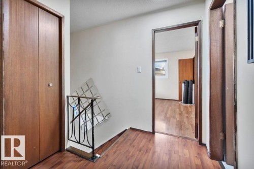 Hallway featuring wood-finish flooring, a bi-fold closet door, and an open doorway leading to an additional room - 712 Lee Ridge Road, Edmonton, AB 