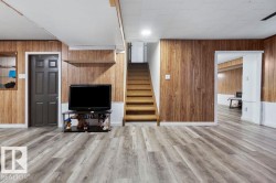 Finished lower level featuring wood-finish flooring, wood paneling, and a neutral color palette - 