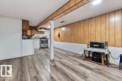 Open-concept living area with wood-finish flooring, wood paneling, and a recessed lighting fixture - 